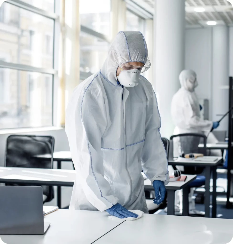 Technicien en combinaison désinfectant des bureaux